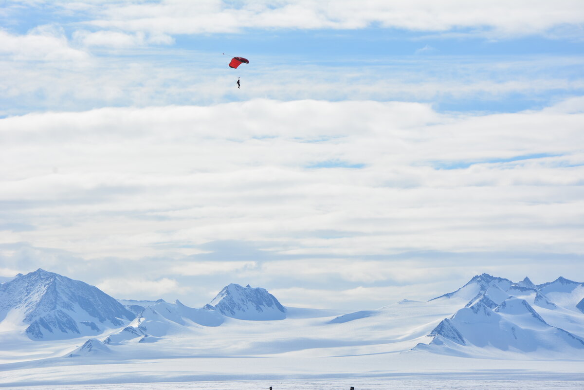 A skydiver steers their parachute towards the landing area