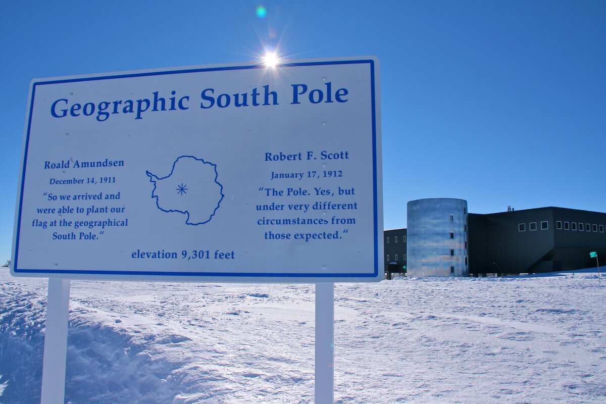 Geographic South Pole Sign with station in background