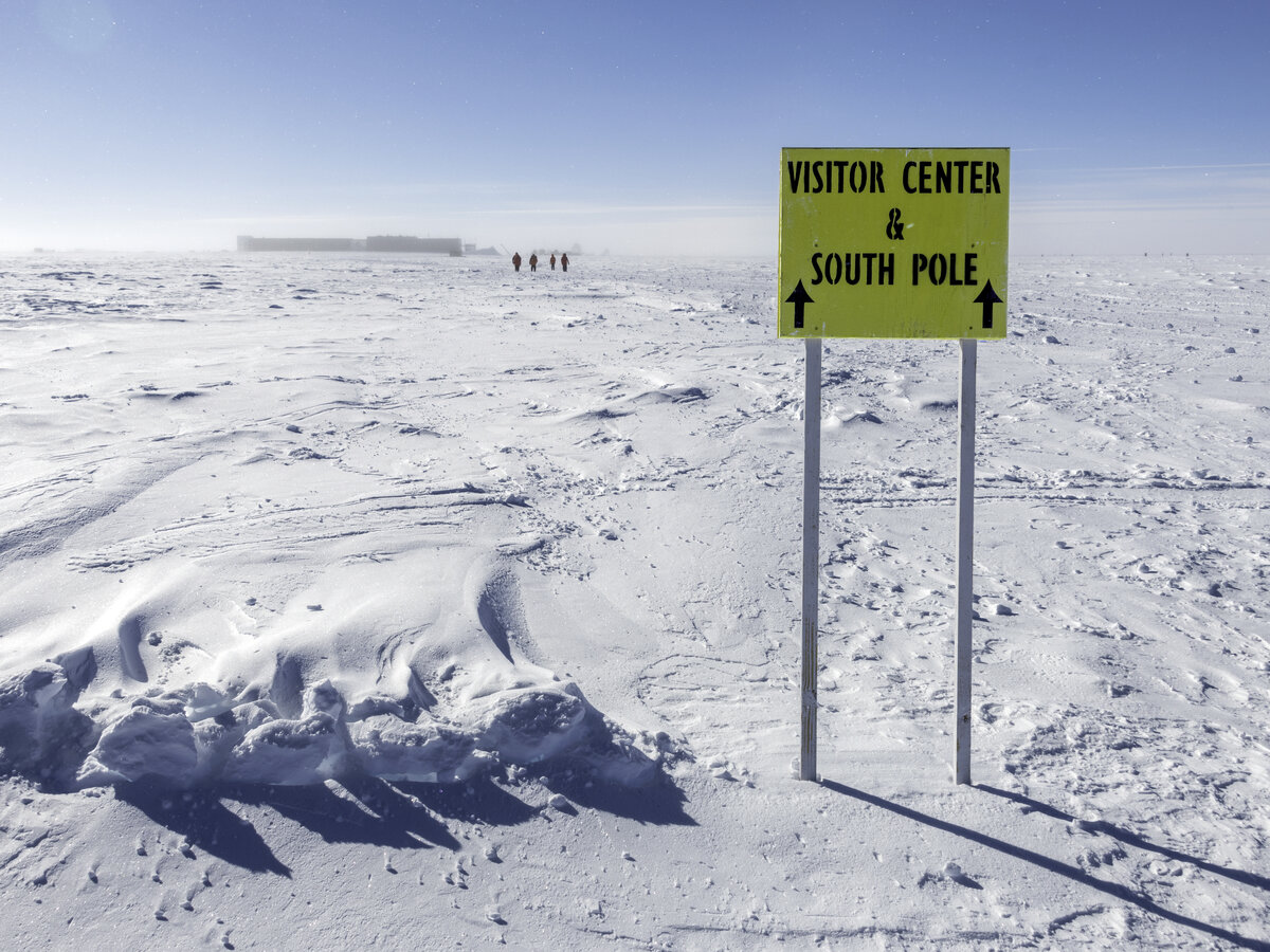 A sign pointing the way to the Visitor Center and South Pole markers